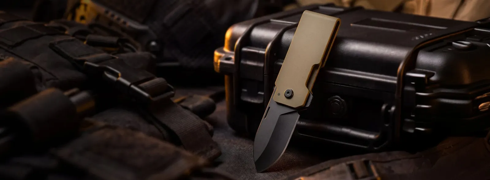 A coyote brown Groove Money Clip Knife open on a dark gear case
