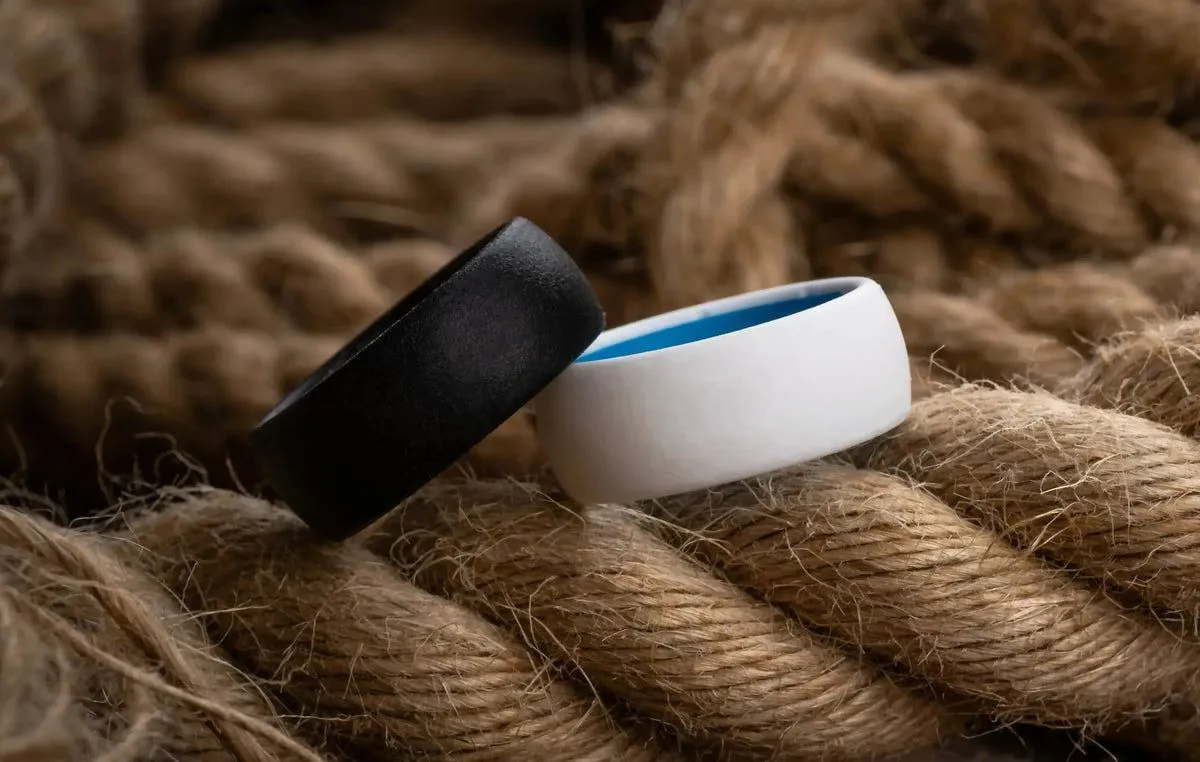 A black Groove ring and a white Groove ring with a blue interior resting on thick rope