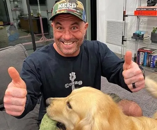 Joe Rogan giving a thumbs up with his golden retriever