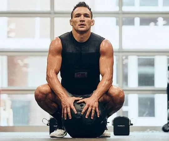 Michael Chandler crouches in workout gear, with a weight ball in front of him
